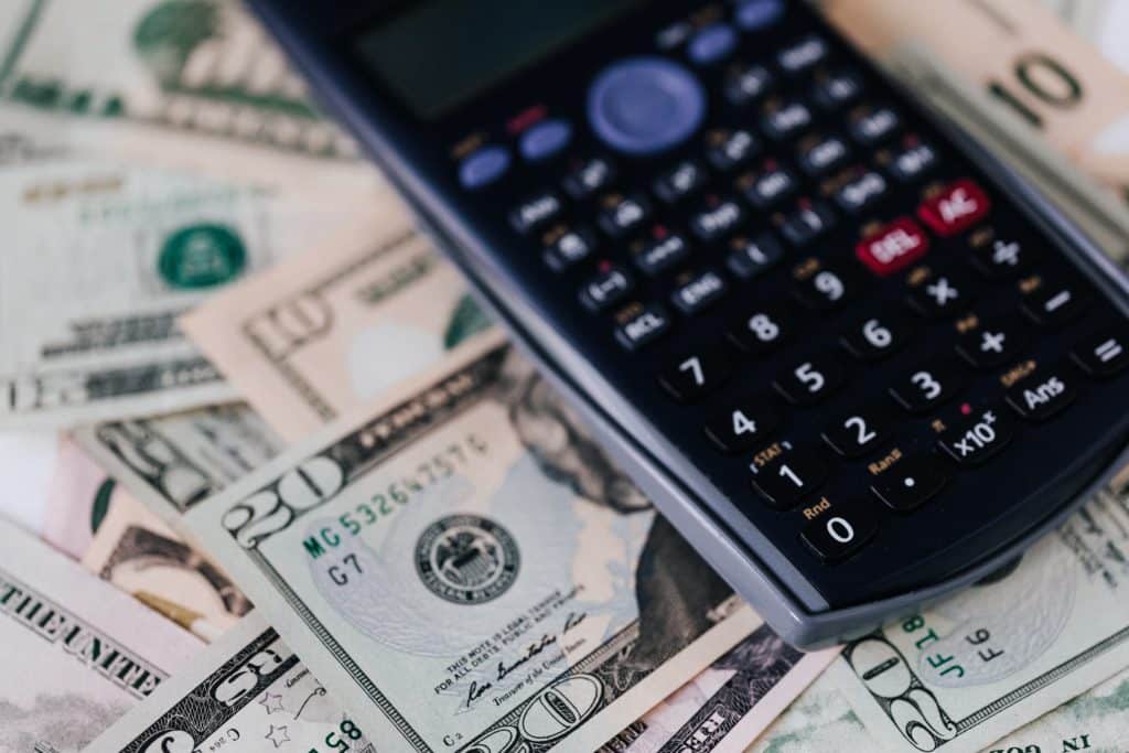 A calculator on top of a pile of money.