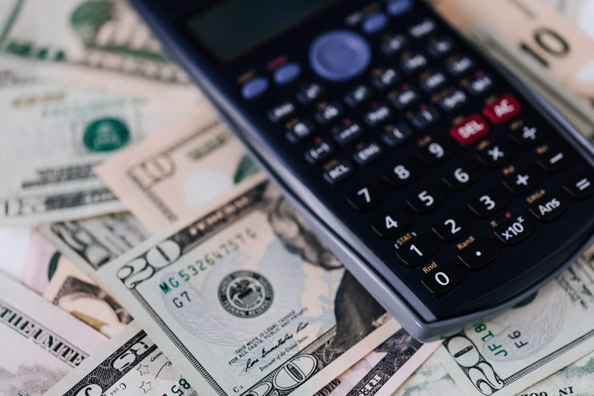 A calculator on top of a pile of money.